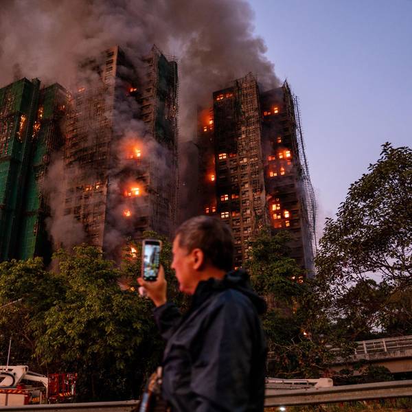 Ein Mann nimmt mit seinem Handy Rauch und Flammen auf, als ein Großbrand mehrere Wohngebäude im Wang Fuk Court in Hongkong erfasst.