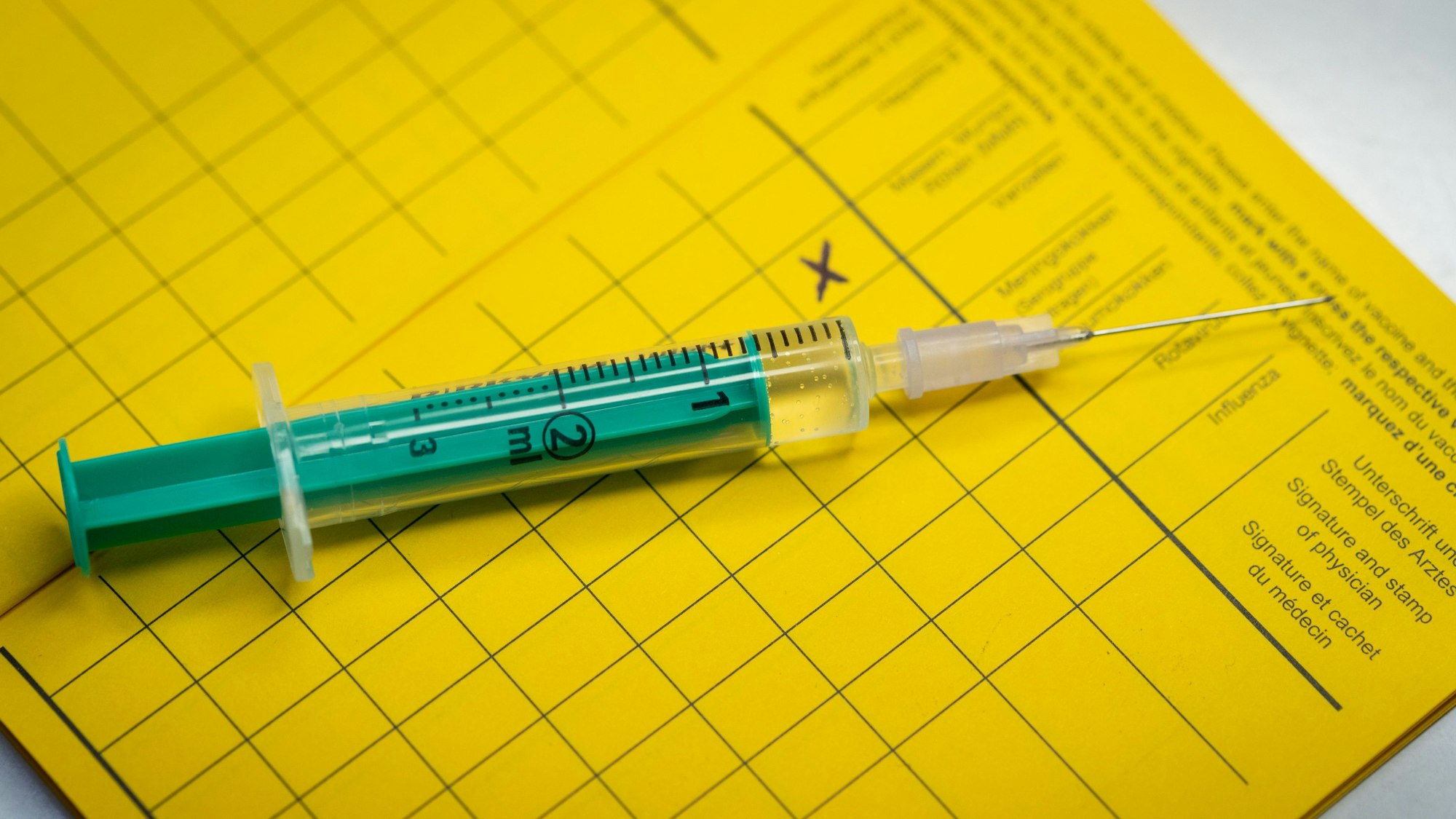 Eine Spritze liegt auf einem Impfpass.