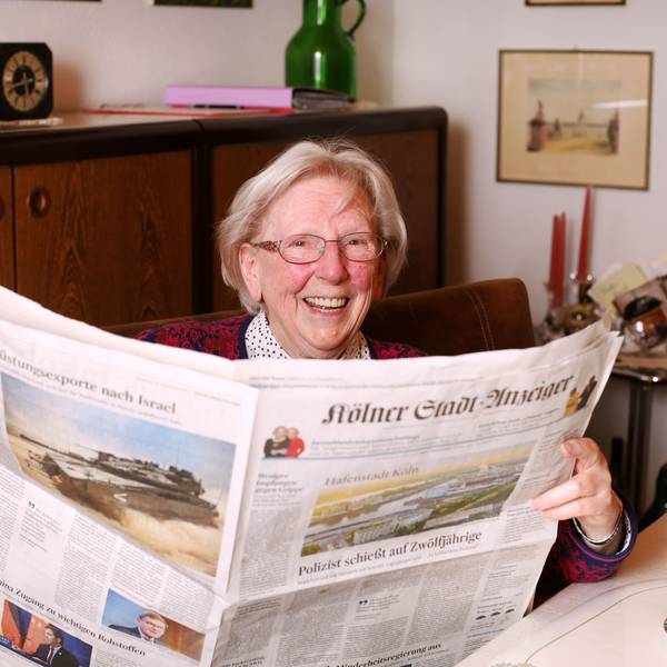 Margot Schoenniger (94) hält den „Kölner Stadt-Anzeiger“ in den Händen und lacht in die Kamera.