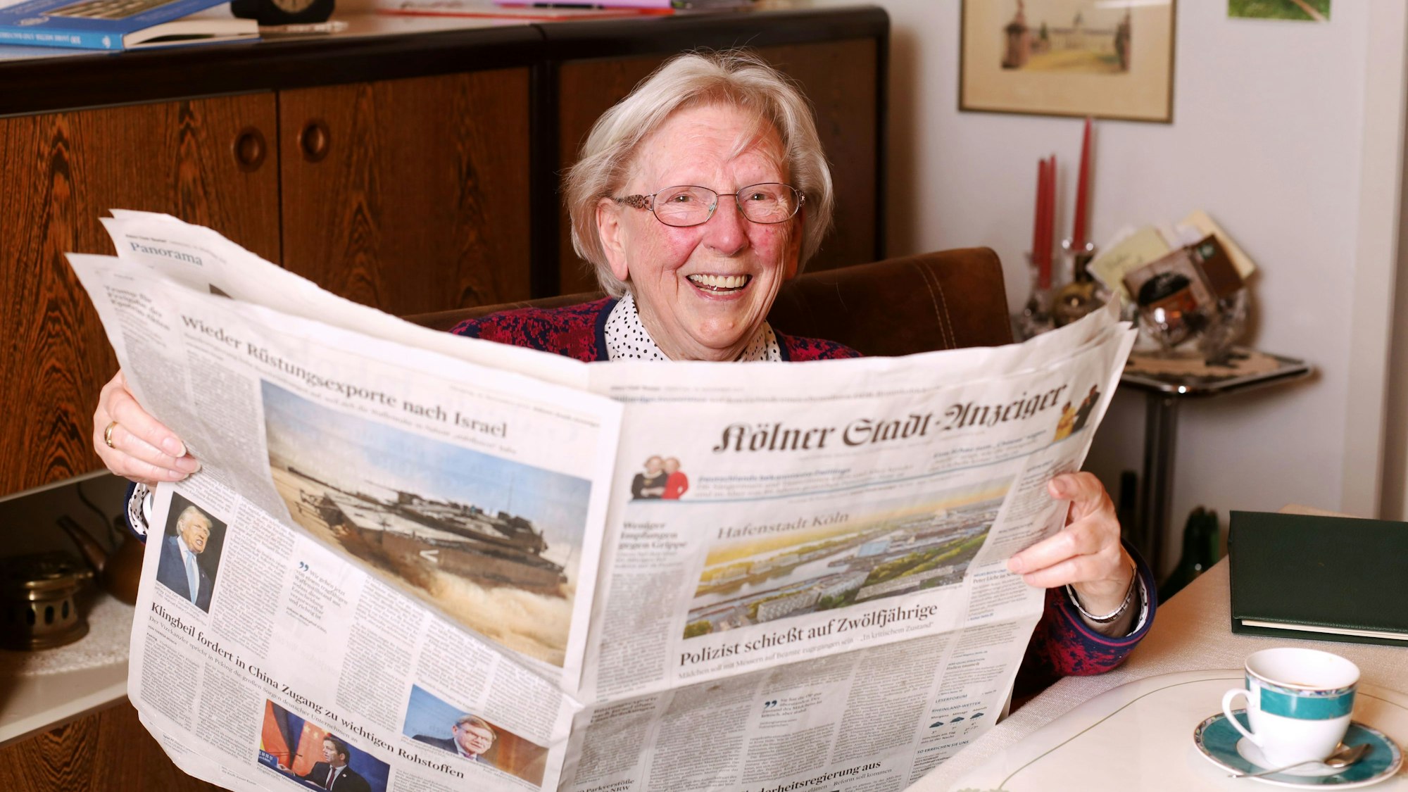 Margot Schoenniger (94) hält den „Kölner Stadt-Anzeiger“ in den Händen und lacht in die Kamera.