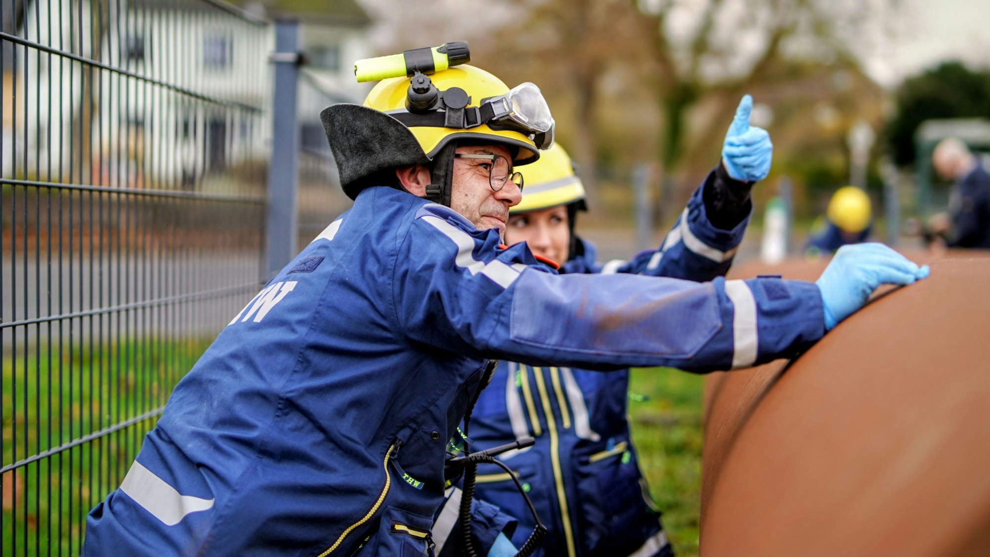 Zwei THW-Mitglieder hantieren an einem großen Stahlrohr.