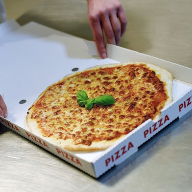 Zu sehen ist eine Pizza im Karton.