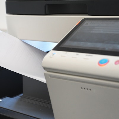 Eine Person holt Papier aus einem Kopierdrucker.