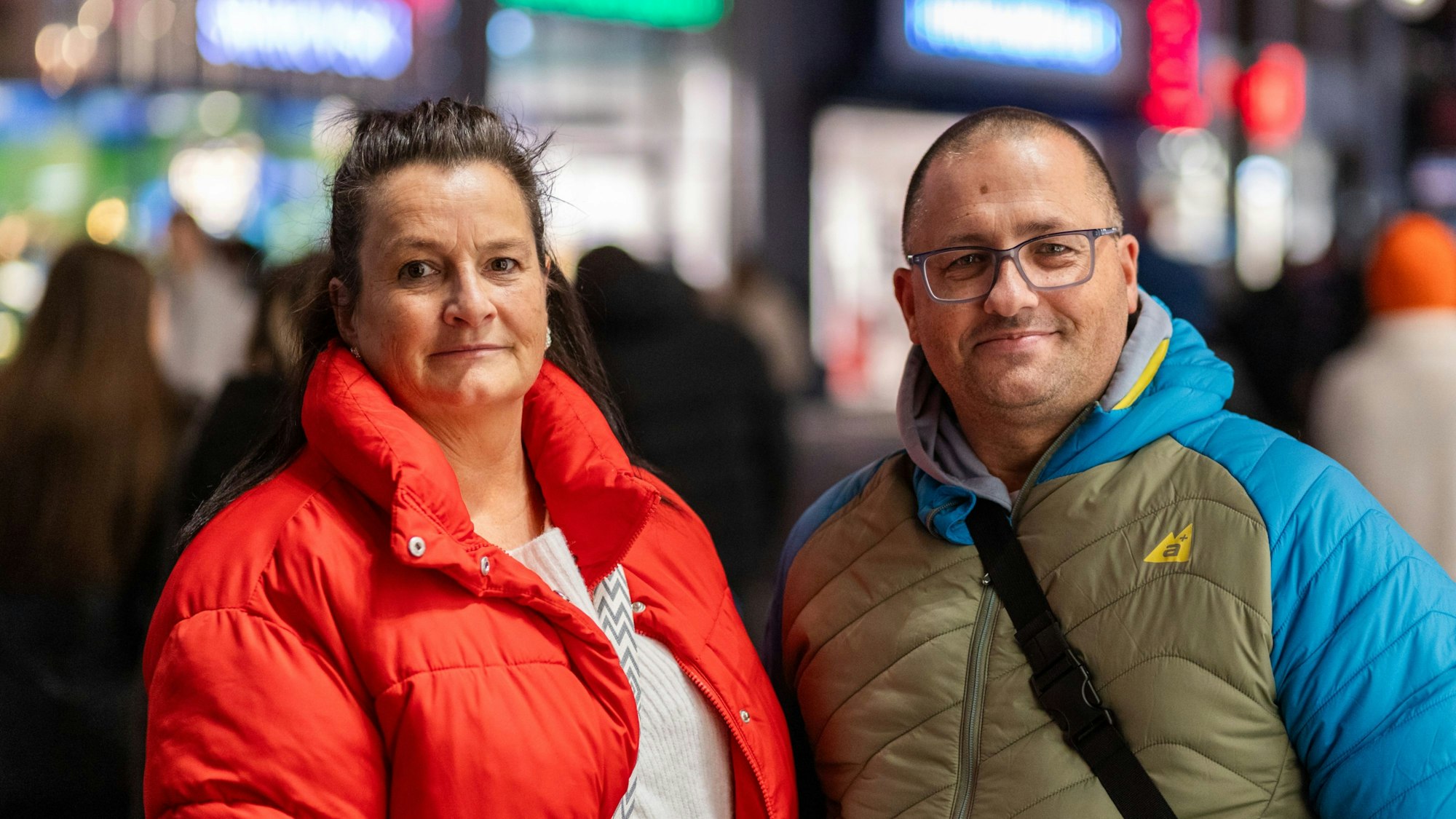 Eine Frau in roter Jacke und ihr Mann lächeln in die Kamera.