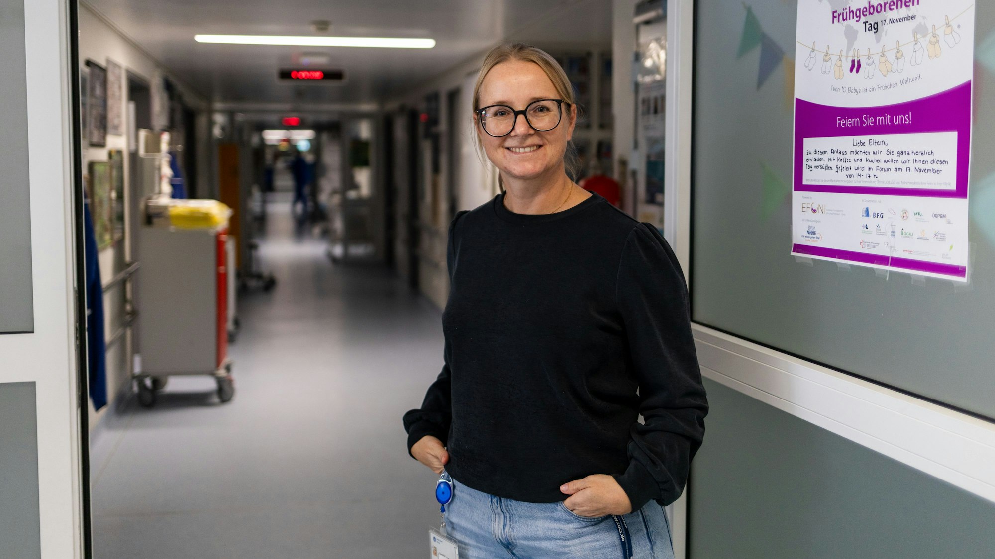 Eine blonde Frau mit Brille und schwarzem Pullover steht im Eingang der Neonatologie.
