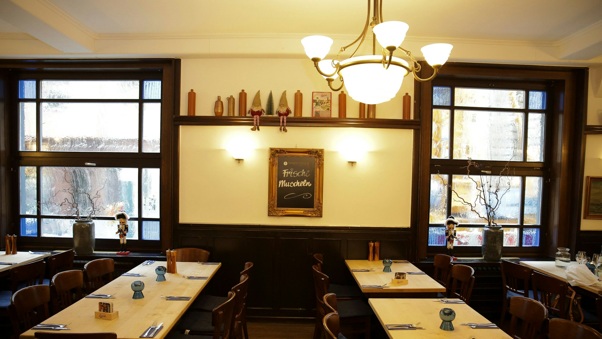 Restaurantraum im Schwan mit dunklen Stühlen und einer Tafel an der Wand auf der Steht „Frische Muscheln“.