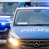 Polizeiautos mit eingeschalteten Scheinwerfern und Blaulicht.