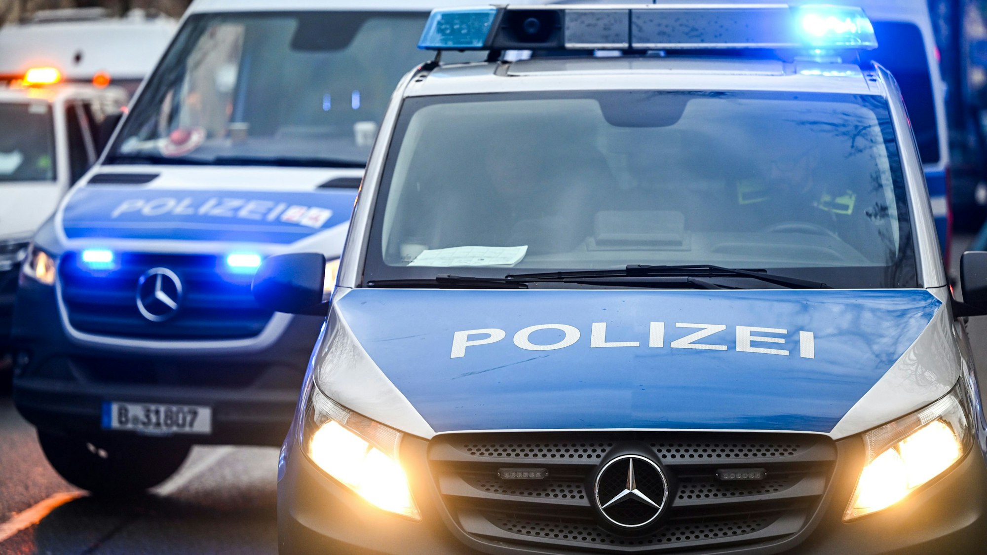 Polizeiautos mit eingeschalteten Scheinwerfern und Blaulicht.