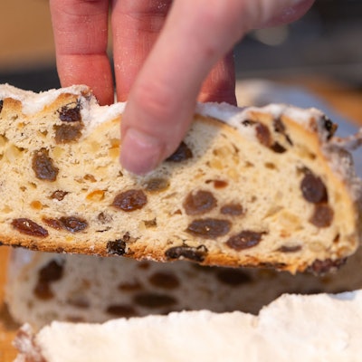 Eine Bäckermeisterin und Konditori zeig eine Scheibe von ihrem Butterstollen.