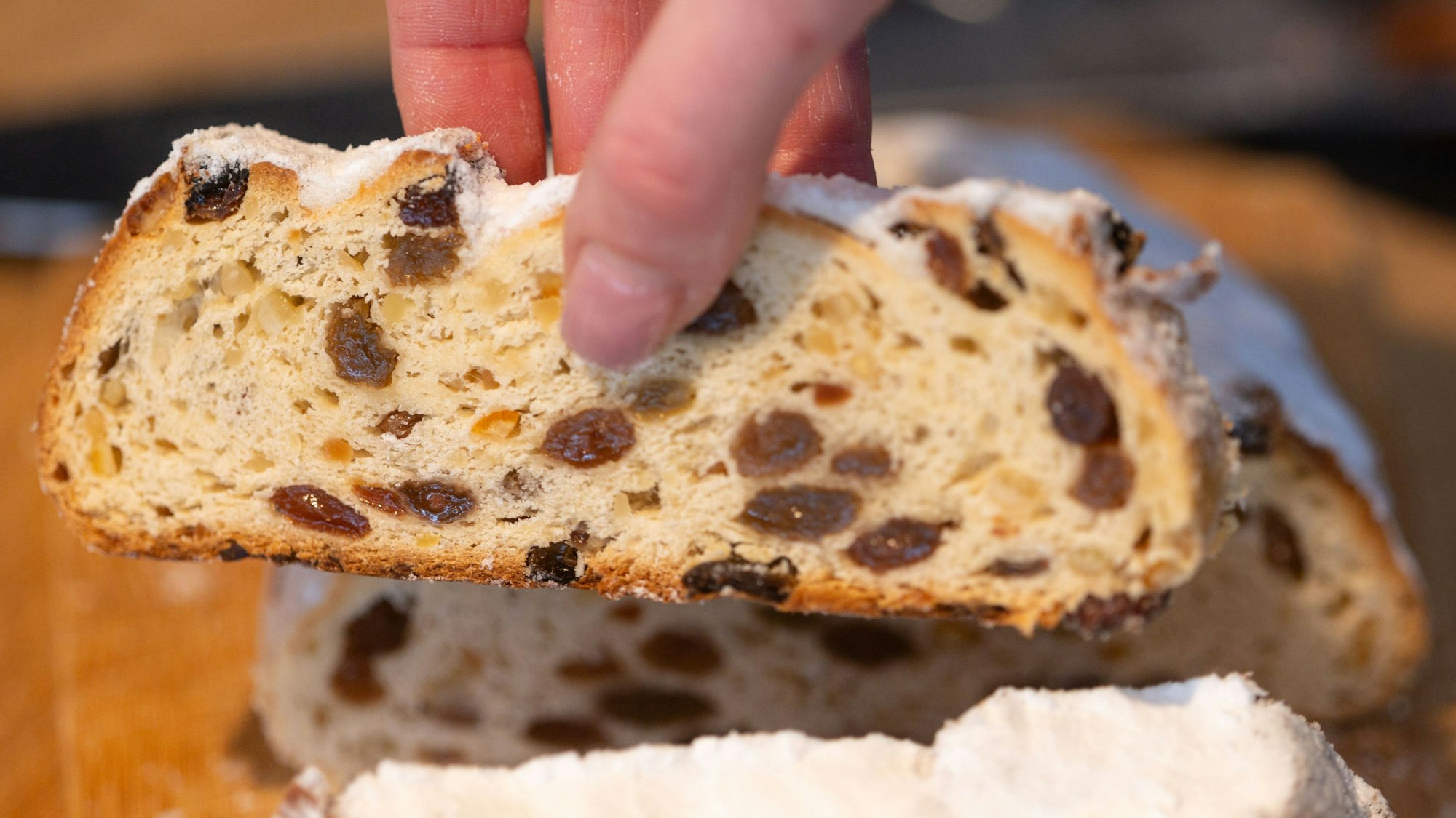 Eine Bäckermeisterin und Konditori zeig eine Scheibe von ihrem Butterstollen.