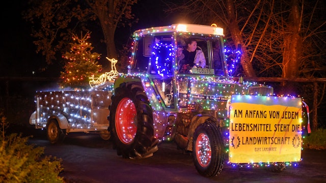 Ein mit bunten Lichterketten geschmückter Traktor.