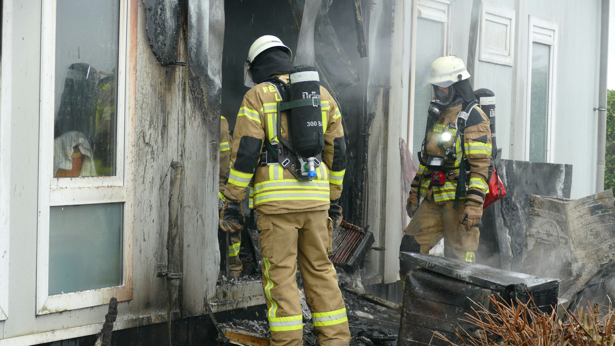 Feuerwehrleute befördern verbrannte Geräte nach draußen.