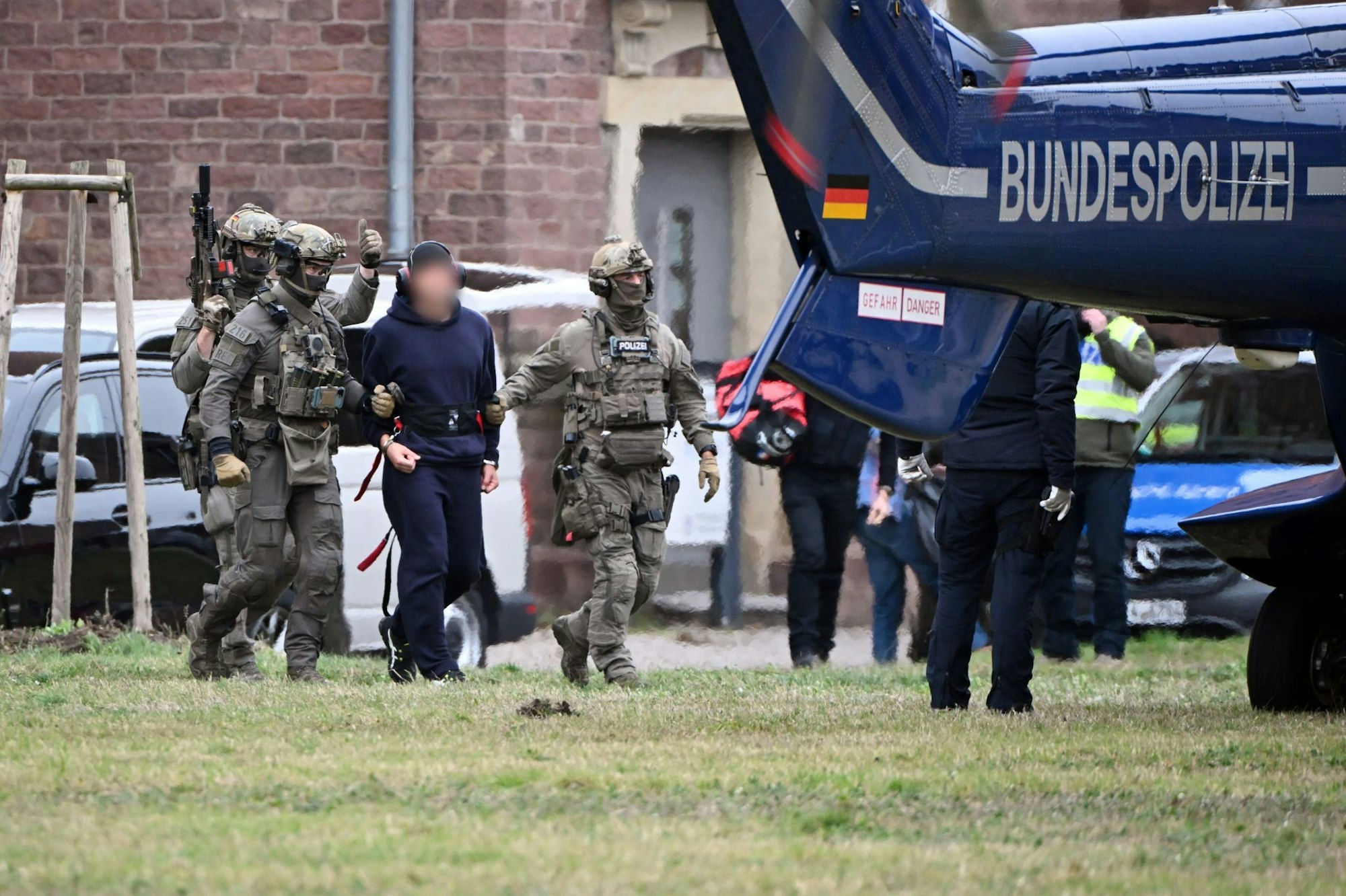 Eine Person wird von Polizeibeamten zu einem Hubschrauber gebracht.