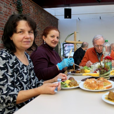 Das Foto zeigt Menschen, die gemeinsam an einem Tisch sitzen und essen.