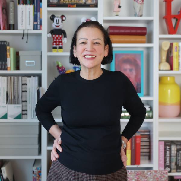 Claudia Malzkorn, Inhaberin der Kölner Kreativagentur Malzkorn, steht vor einem Regal mit bunten Design-Gegenständen und Büchern