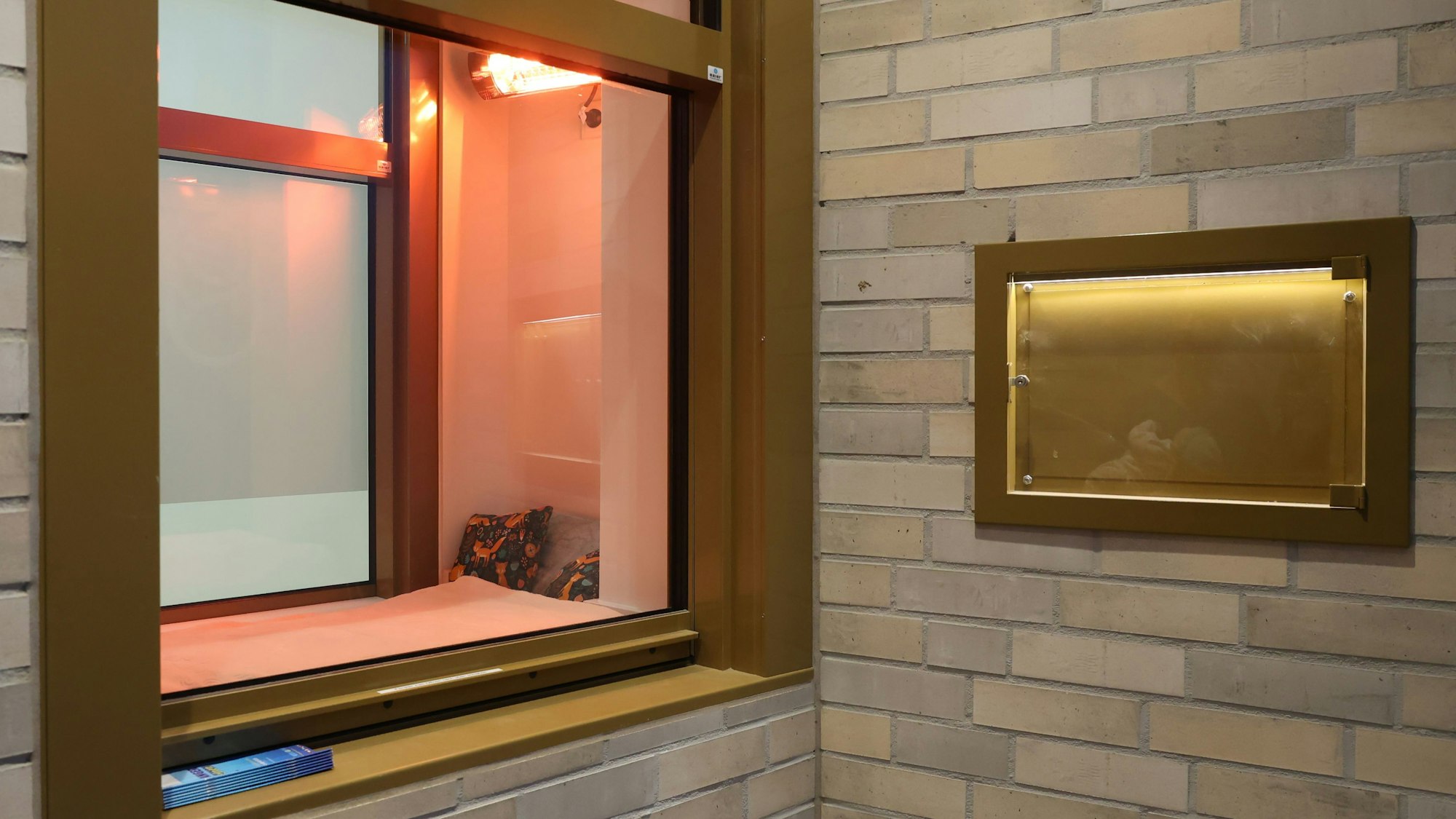 Hinter dem Kölner Moses-Fenster befindet sich ein Wärmebettchen, davor Informationen über Hilfsangebote für die Mütter.