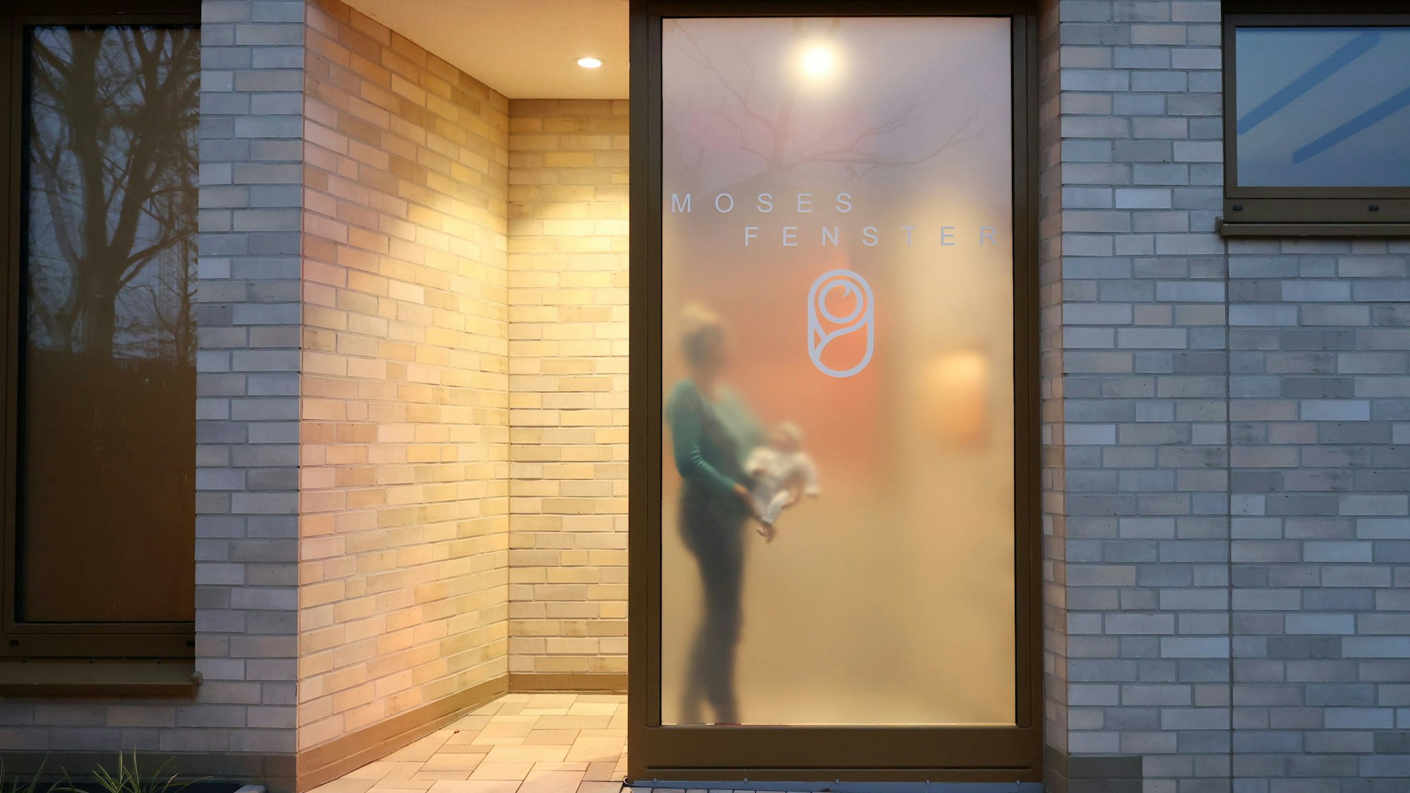 In diesem gestellten Foto geht eine Mitarbeiterin des SkF mit Baby (hier in Form einer Übungspuppe) zum Moses-Fenster.