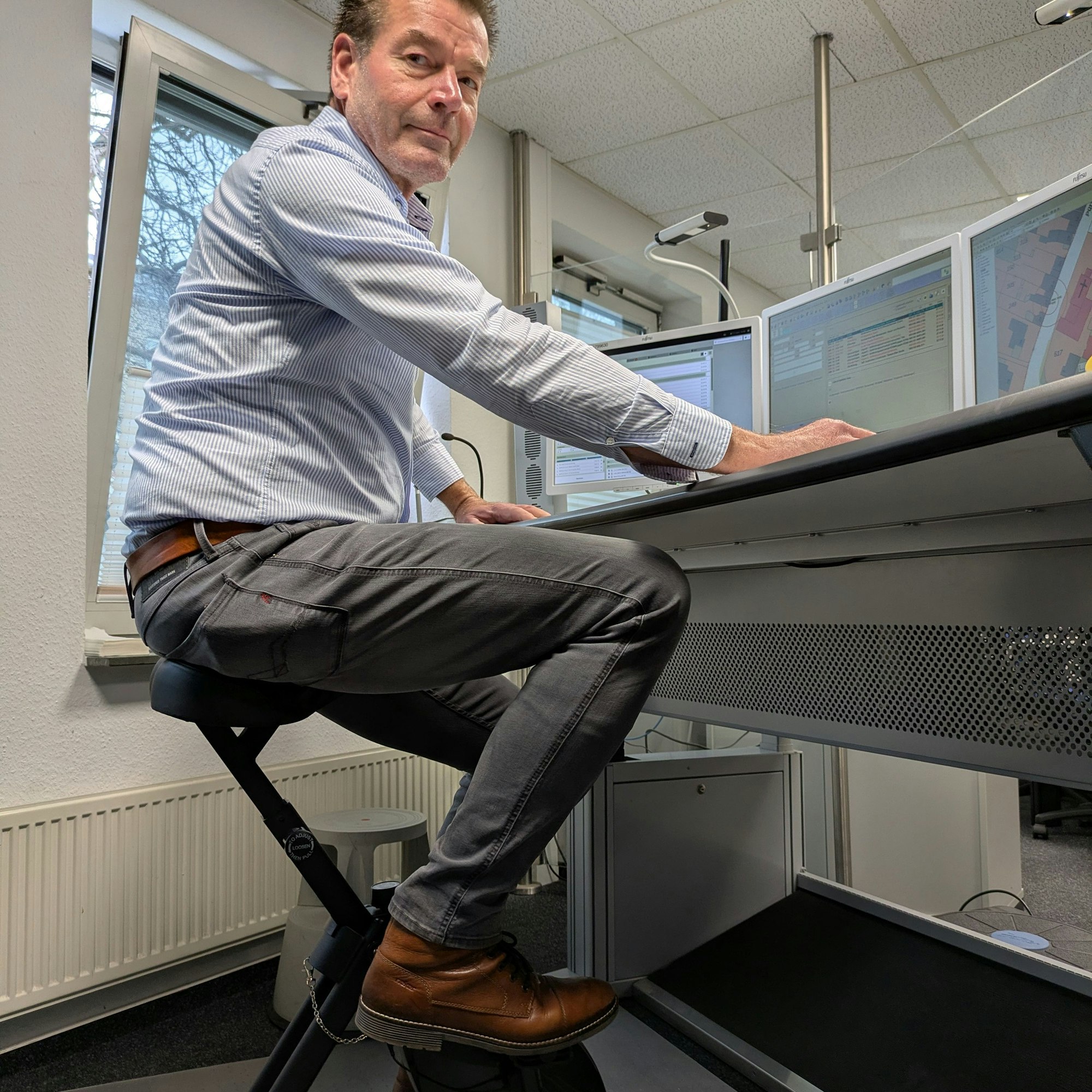 Ulrich Linden sitzt vor Computern und tritt leicht in die Pedale.