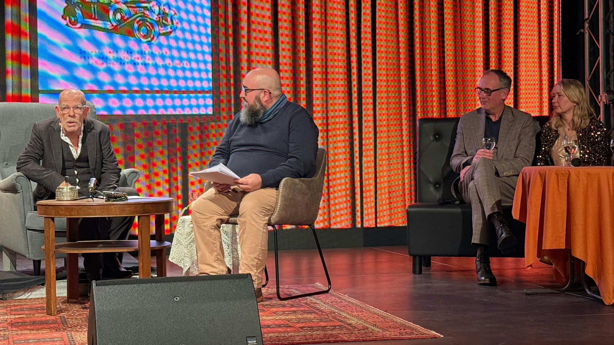 Zwei Herren an einem Tisch, ein Mann und eine Frau an einem anderen.