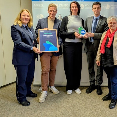 Auf einem Gruppenfoto präsentieren die Beteiligten die Trophäe und die Urkunde.