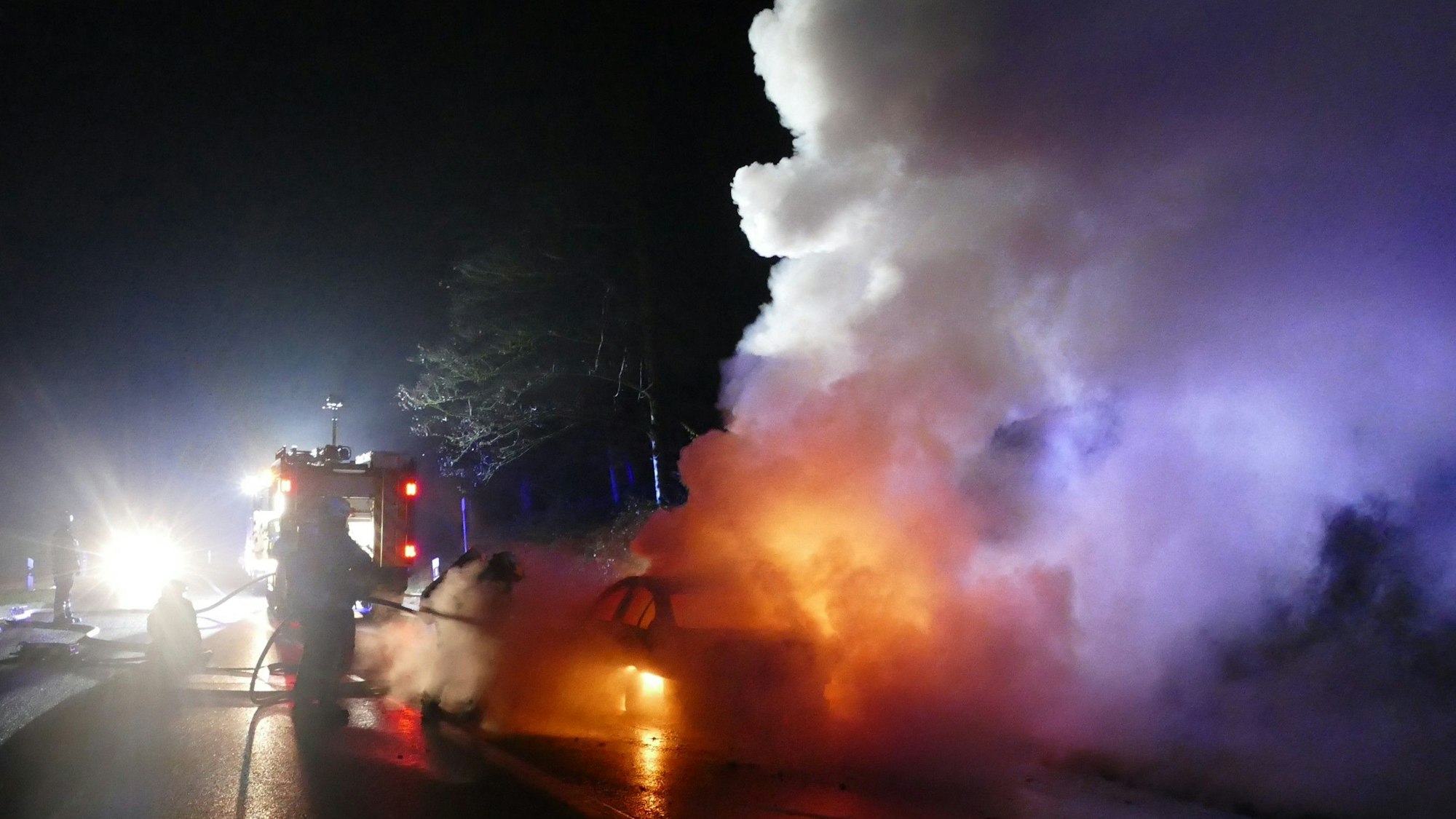 Die Feuerwehr löscht ein brennendes Auto.