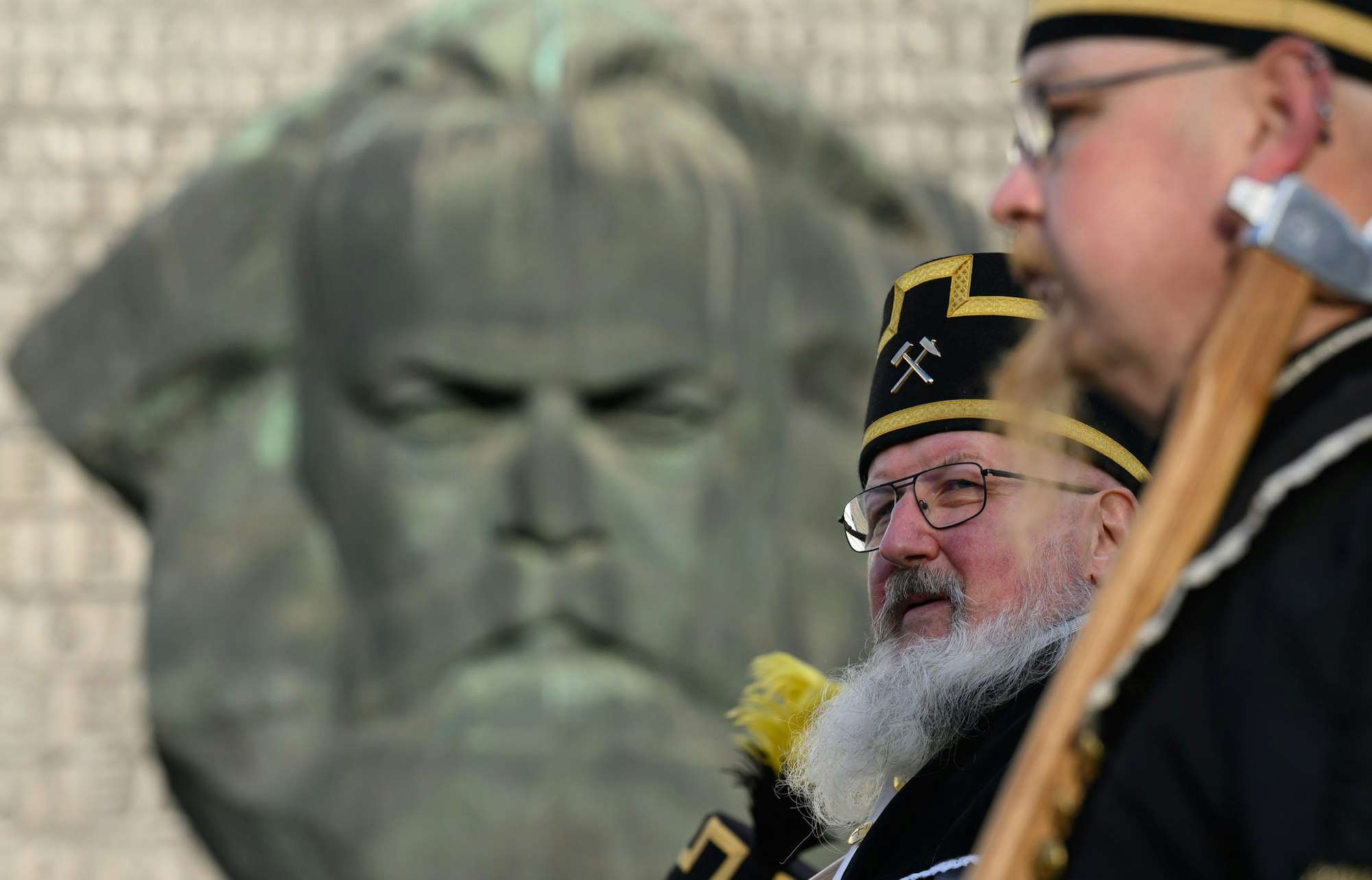 Zum Abschluss des Kulturhauptstadtjahres in Chemnitz ziehen Teilnehmer der Bergparade im traditionellen Habit am Karl-Marx-Monument vorbei.