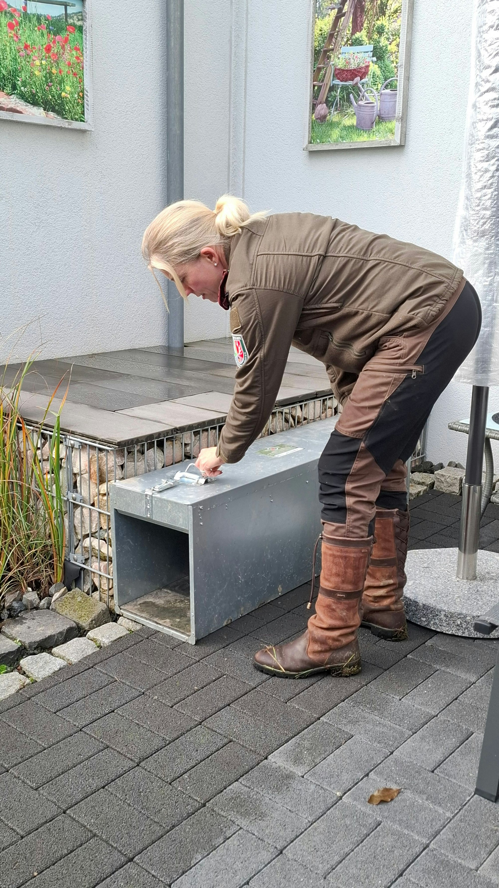 Katharina Salawa kontrolliert eine Lebendfalle in einem privaten Garten.