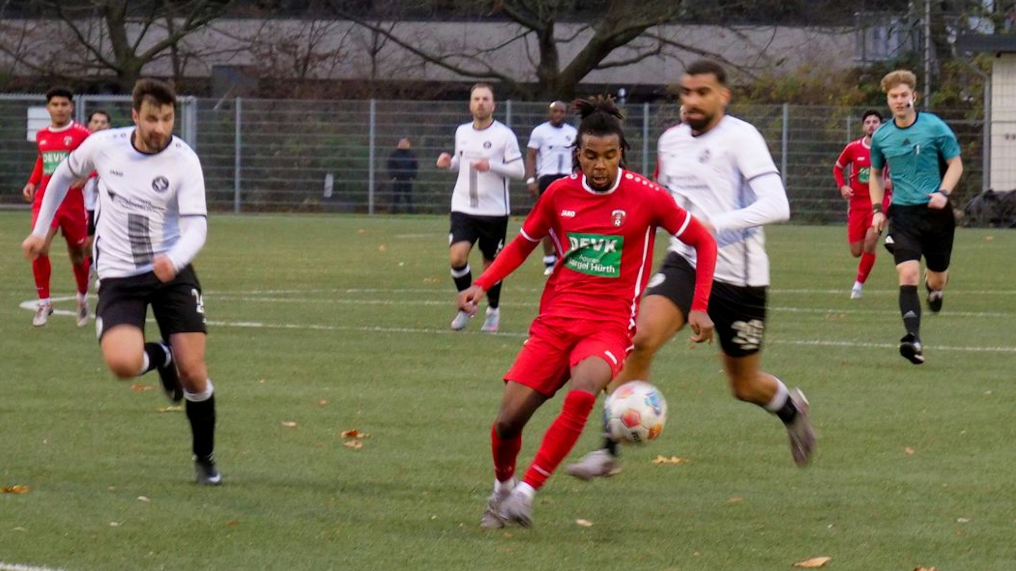 Das Bild zeigt einen Hürther Fußballer im roten Trikot, der mit dem Ball auf dem Weg zum Ausgleich ist.