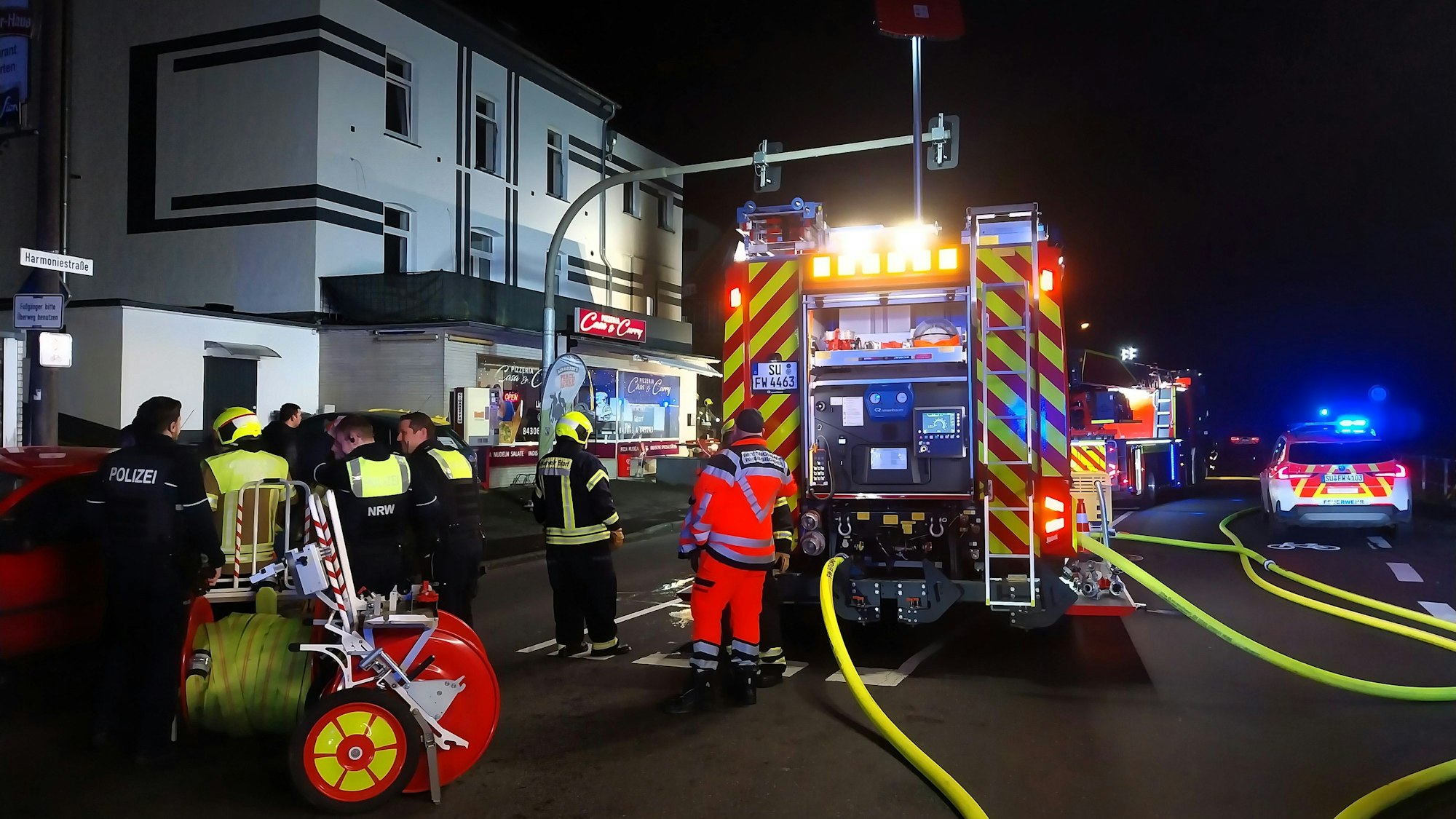 Ein Feuerwehrauto, Löschschläuche und Helfer in Uniform.