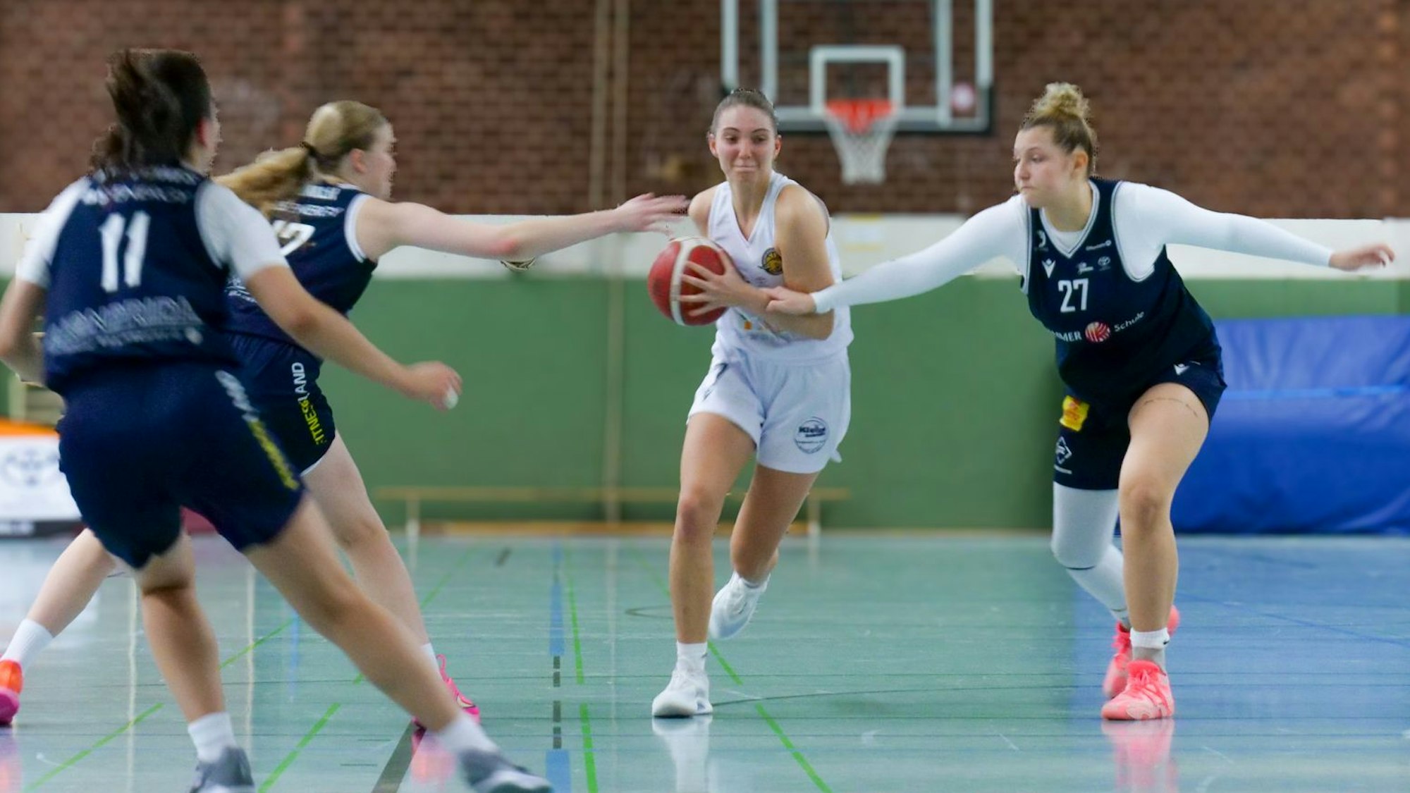 Das Bild zeigt die Hürther Basketballerin Mara Wiese, die mit Ball durch drei Gegnerinnen durchläuft.