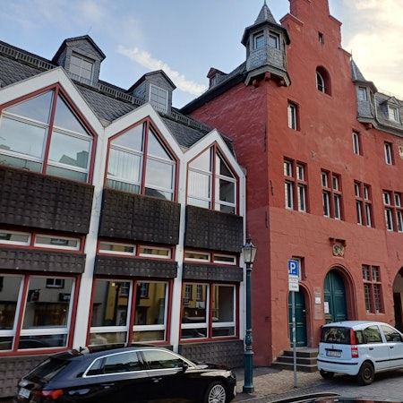 Das Bild zeigt das Rathaus, davor stehen Autos.