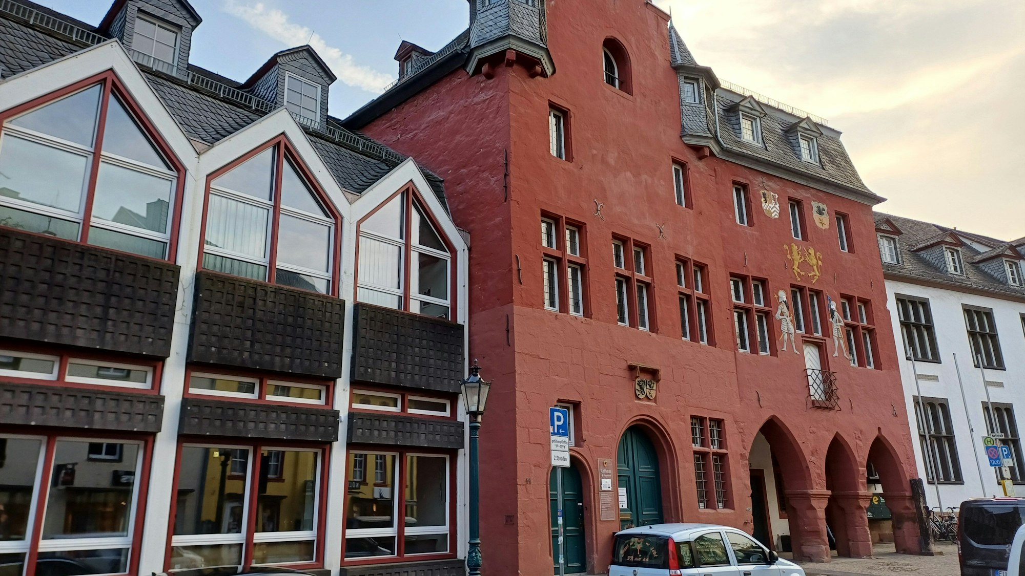 Das Bild zeigt das Rathaus, davor stehen Autos.