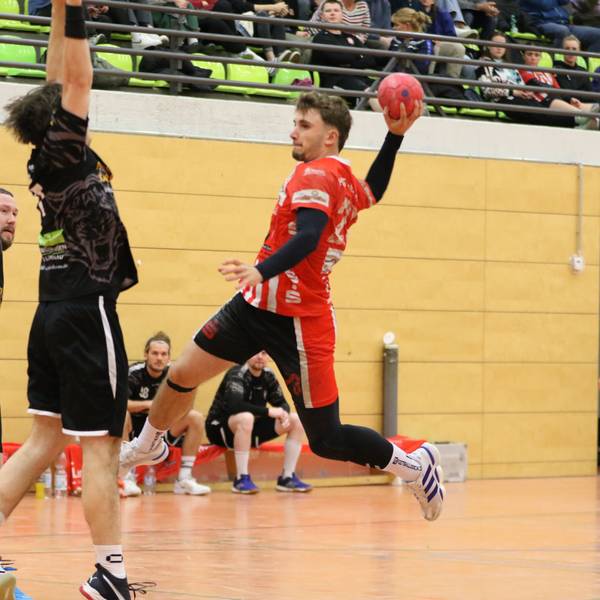 Schreiber ist zum Sprungwurf hochgestiegen. Ein Abwehrspieler versucht, den Ball zu blocken.