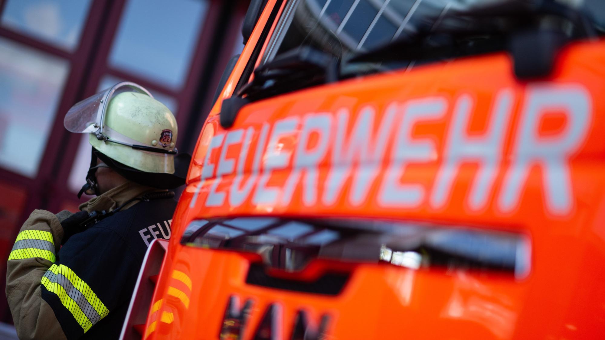 Eine Einsatzkraft der Feuerwehr steht neben einem Einsatzfahrzeug der Feuerwehr (gestellte Szene). (zu dpa: «Ein Toter bei Wohnungsbrand in Ketsch») +++ dpa-Bildfunk +++