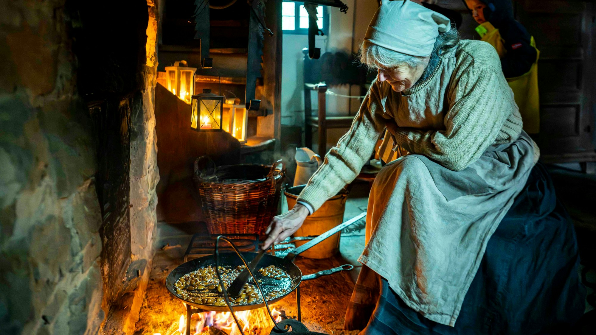 Das Bild zeigt Andrea Rolfes-Koenen in einem historischen Outfit, während sie in einer Pfanne Mandeln zubereitet.