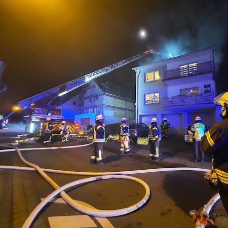 Eine ausgefahrene Drehleiter an einem Mehrfamilienhaus.