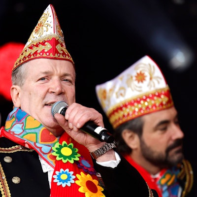 Christoph Kuckelkorn mit Narrrenkappe und Mikro in der Hand.