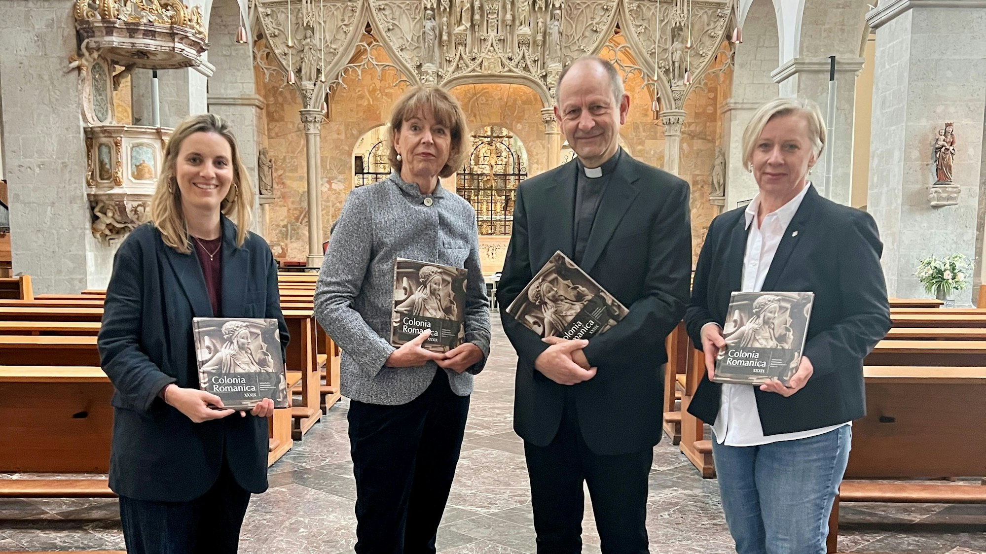 Bei der Buchvorstellung stehen in St. Pantaleon (v.l.): Verlegerin Franziska Emons-Hausen, Henriette Reker, Vorsitzende des Fördervereins Romanische Kirchen Köln, Volker Hildebrandt, Pfarrer an St. Pantaleon, und Gabriele Oepen-Domschky, Geschäftsführerin des Fördervereins.