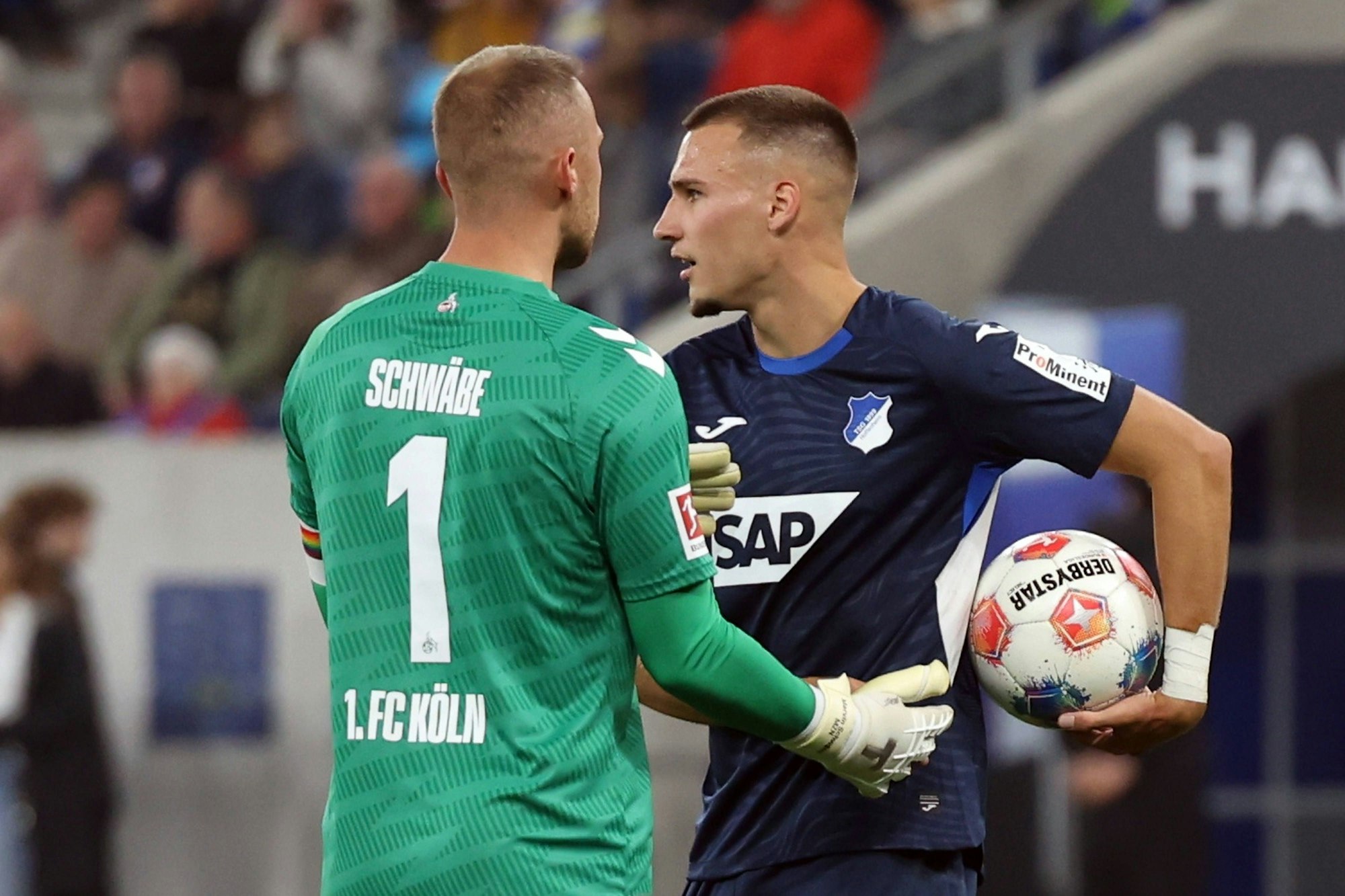 Tim Lemperle von der TSG 1899 Hoffenheim im Gespräch mit FC-Torhüter Marvin Schwäbe während des Bundesliga-Spiels in Sinsheim.
