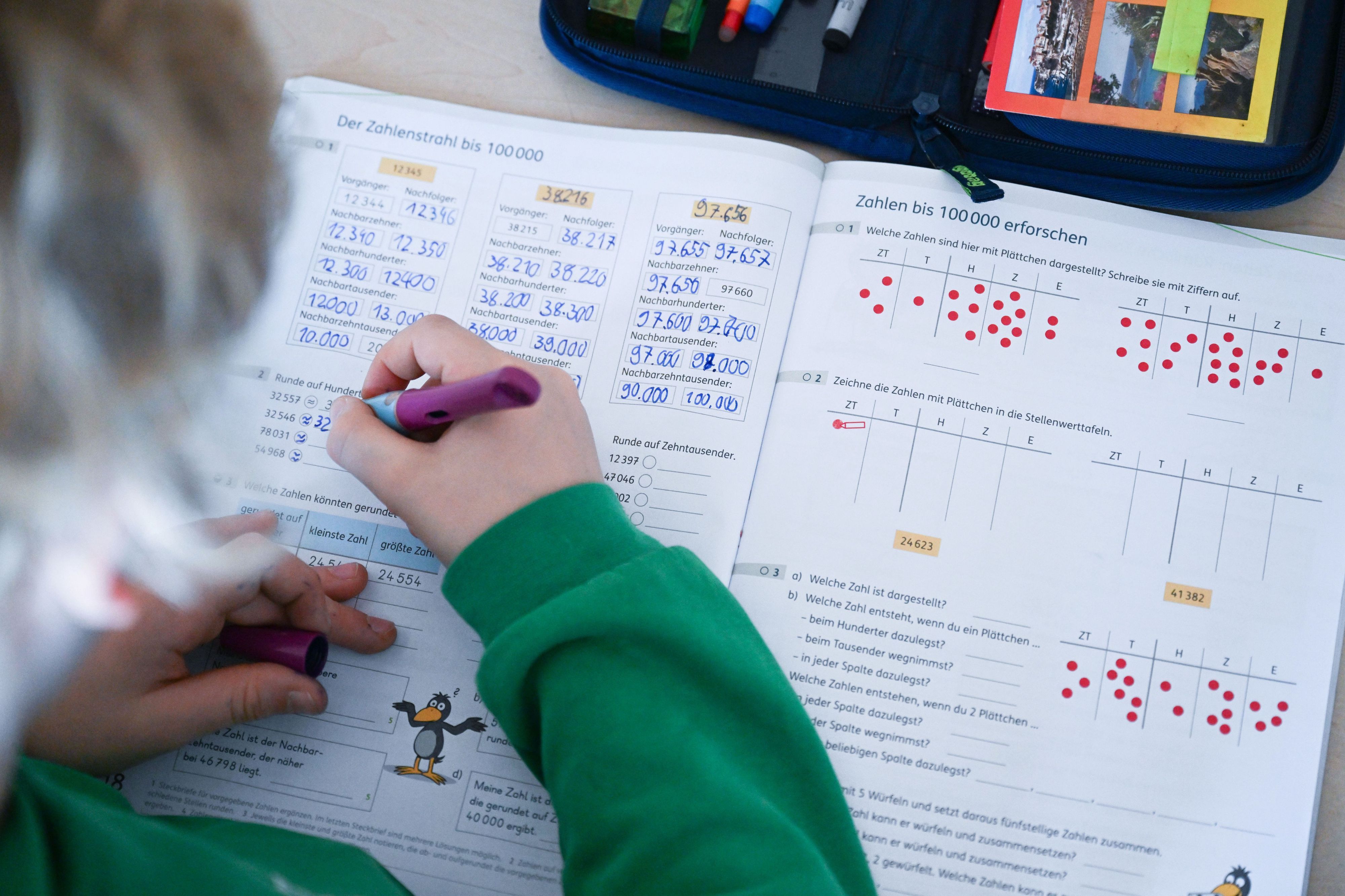 In einer Grundschule arbeitet ein Schüler einer vierten Klasse in einem Heft an seinen Mathematikaufgaben.