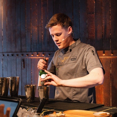 Das Bild zeigt Jakob Schröder hinter der Theke beim Mixen.