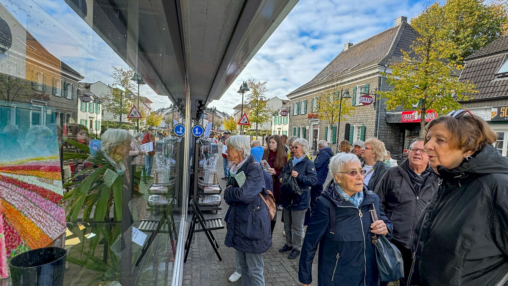 Anwohnerinnen und Anwohner schauen sich die Werke bei „Kunst in Schlebuscher Schaufenstern“ an.