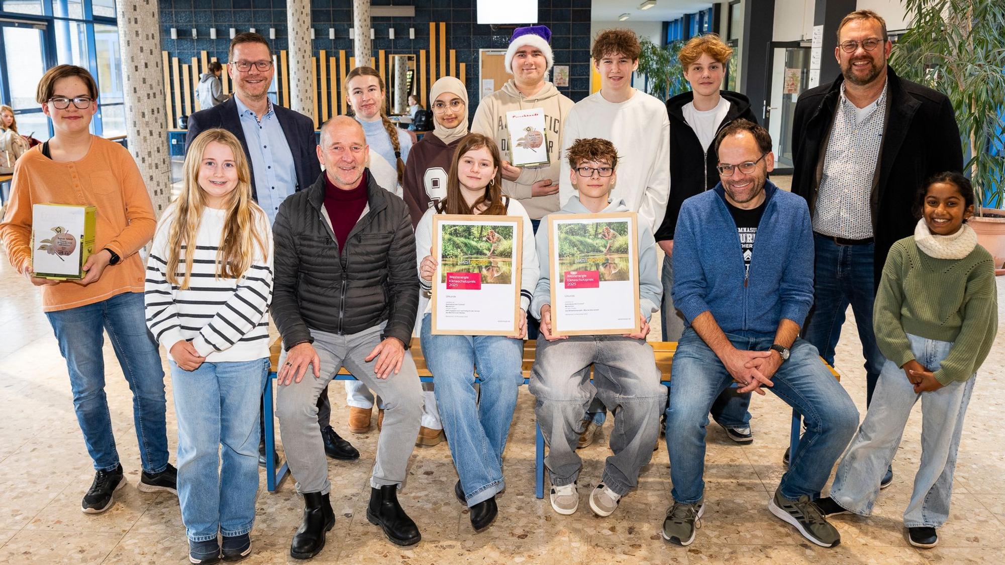 Jugendliche und Erwachsene haben sich zum Gruppenbilde formiert. Ein Junge und ein Mädchen halten die Urkunden.