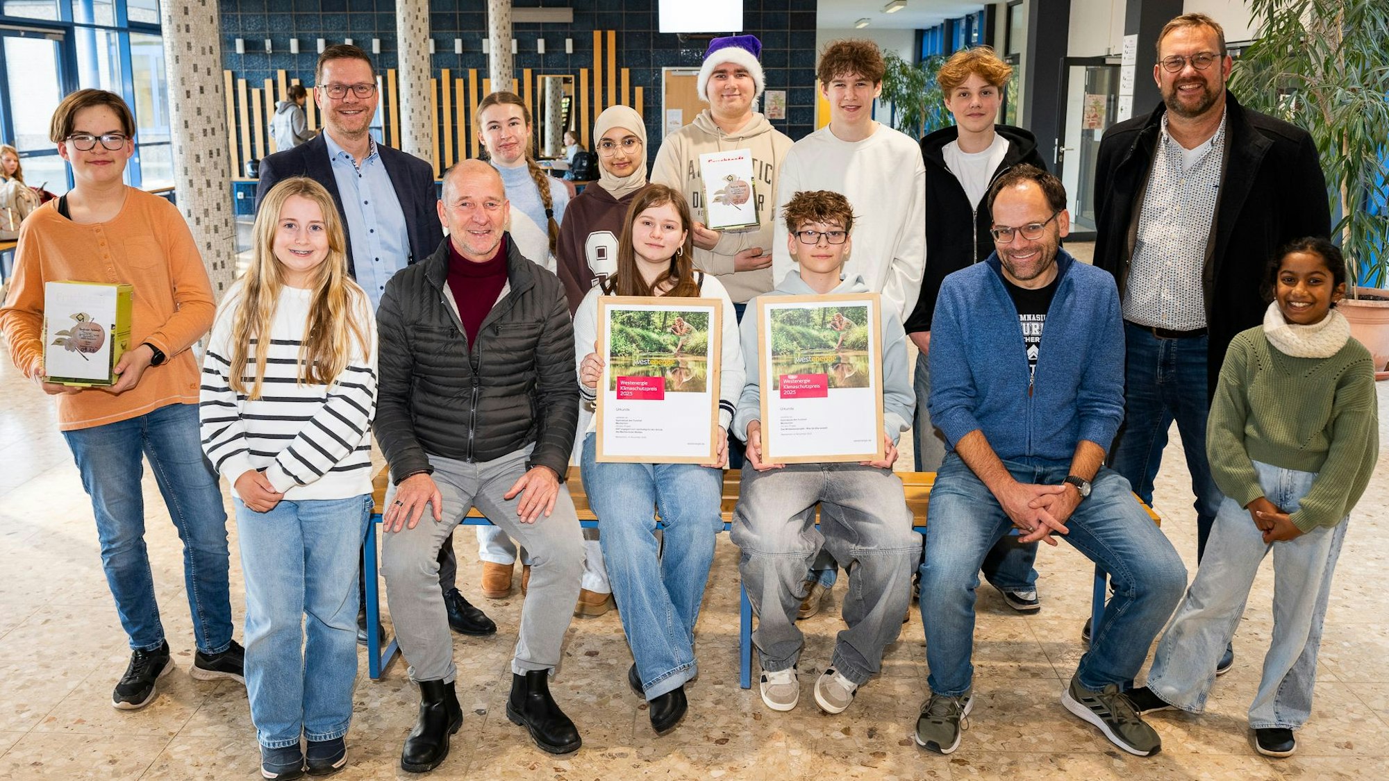 Jugendliche und Erwachsene haben sich zum Gruppenbilde formiert. Ein Junge und ein Mädchen halten die Urkunden.