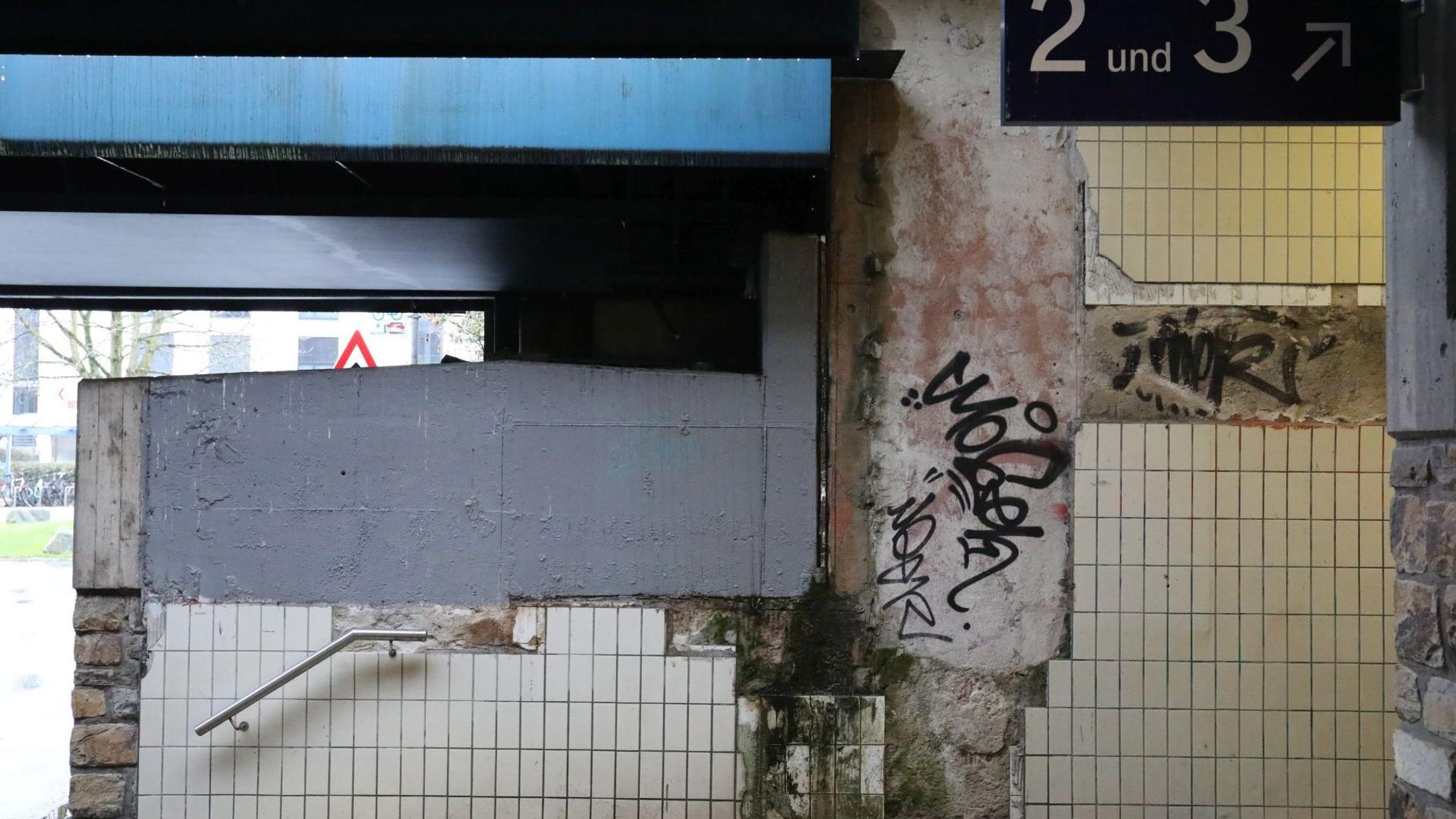 Ein hässlicher, gefliester und mit Graffiti versehener Aufgang zum Bahnhof.
