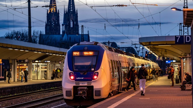 Das Bild zeigt einen Zug des Betreibers National Express im Bahnhof Köln-Deutz. Im Hintergrund ist der Kölner Dom zu sehen. Foto: IMAGO/Jochen Tack