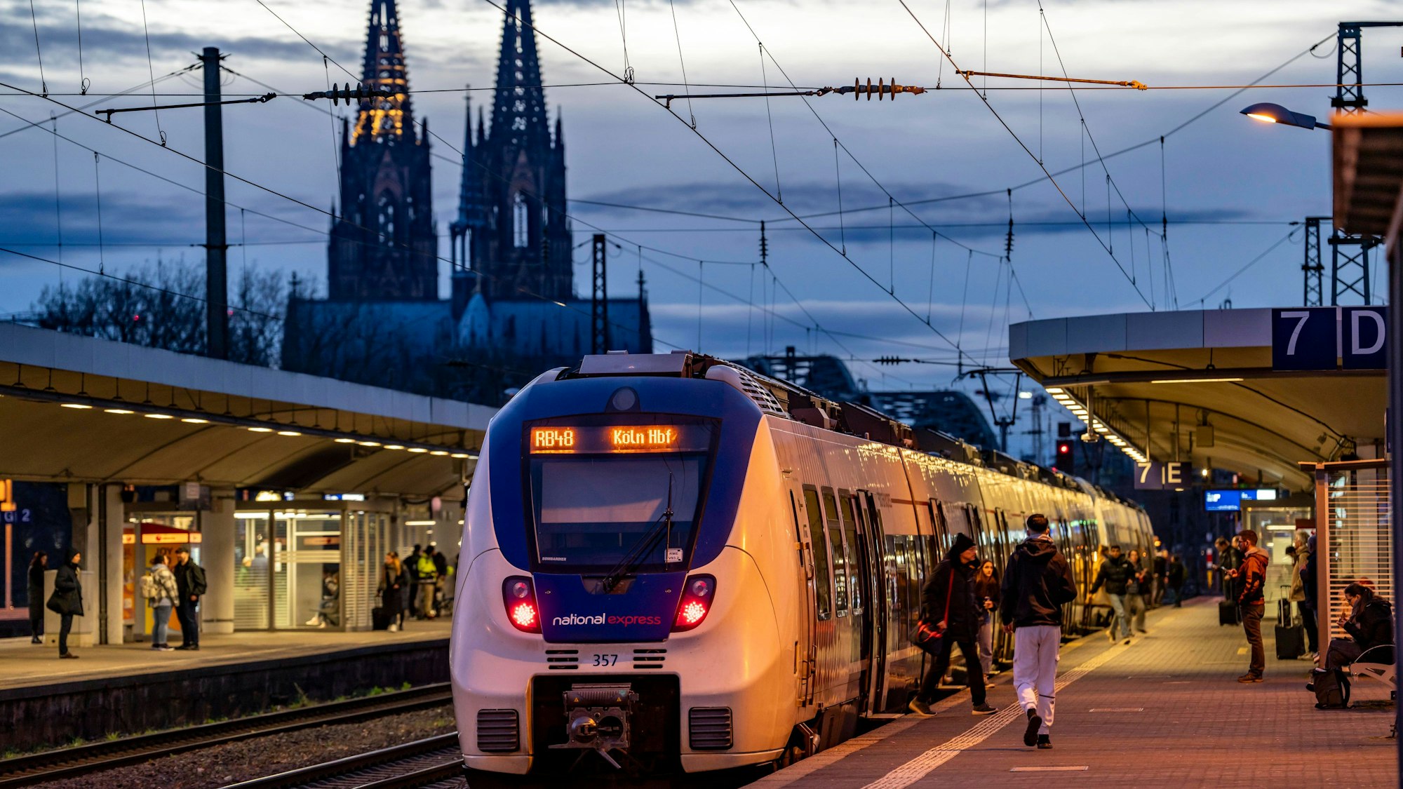 Das Bild zeigt einen Zug des Betreibers National Express im Bahnhof Köln-Deutz. Im Hintergrund ist der Kölner Dom zu sehen. Foto: IMAGO/Jochen Tack