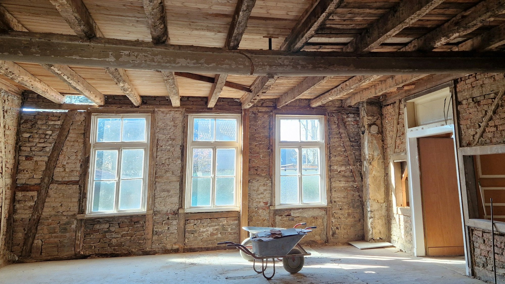 Blick in einen ehemaligen Saal, in dem Wand- und Deckenverkleidungen entfernt wurden.