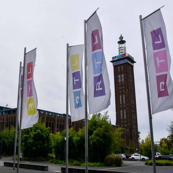Der Kölner Messe Turm, davor bunte Fahnen mit dem RTL Logo in Deutz am Picassoplatz