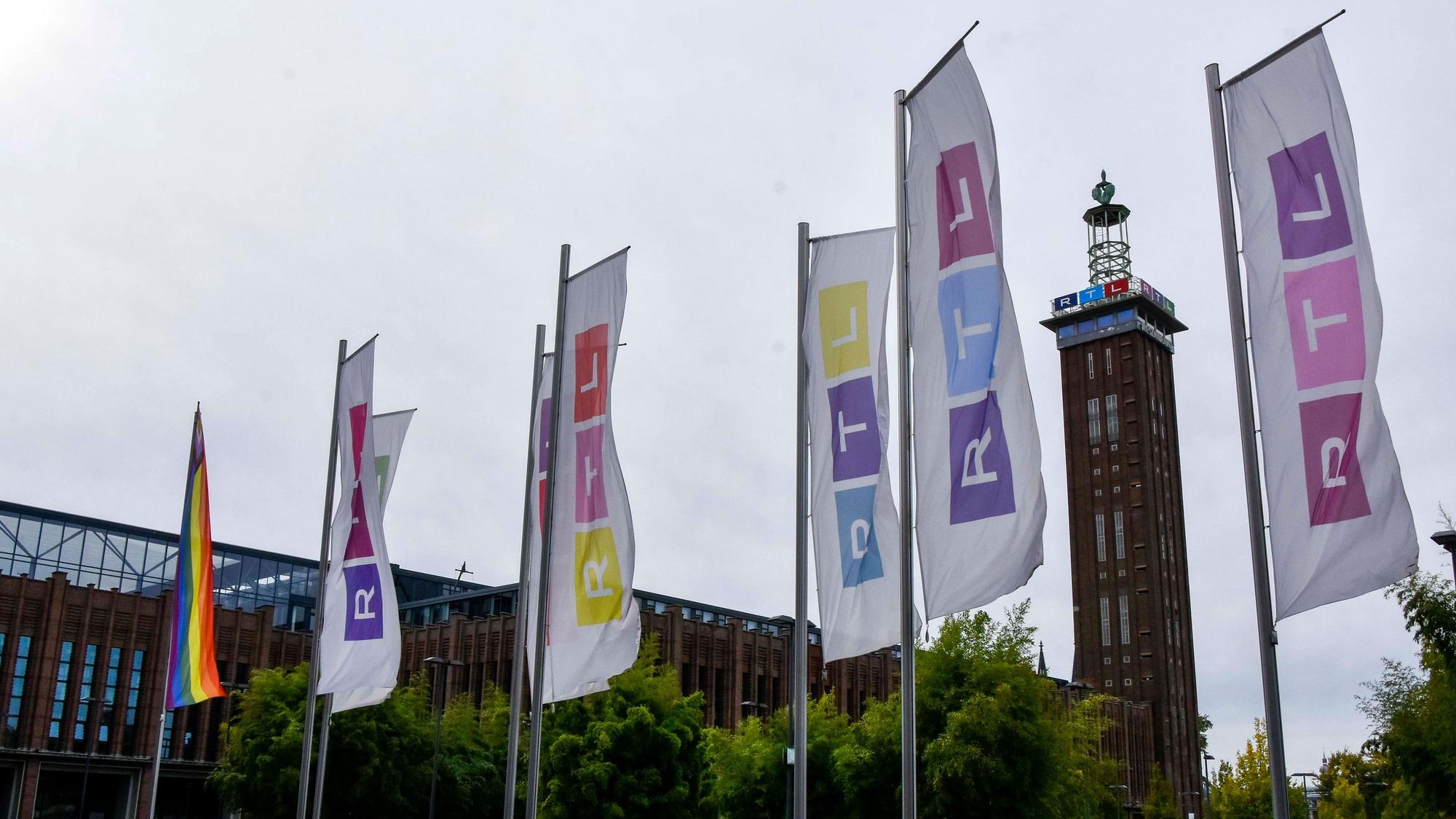 Der Kölner Messe Turm, davor bunte Fahnen mit dem RTL Logo in Deutz am Picassoplatz